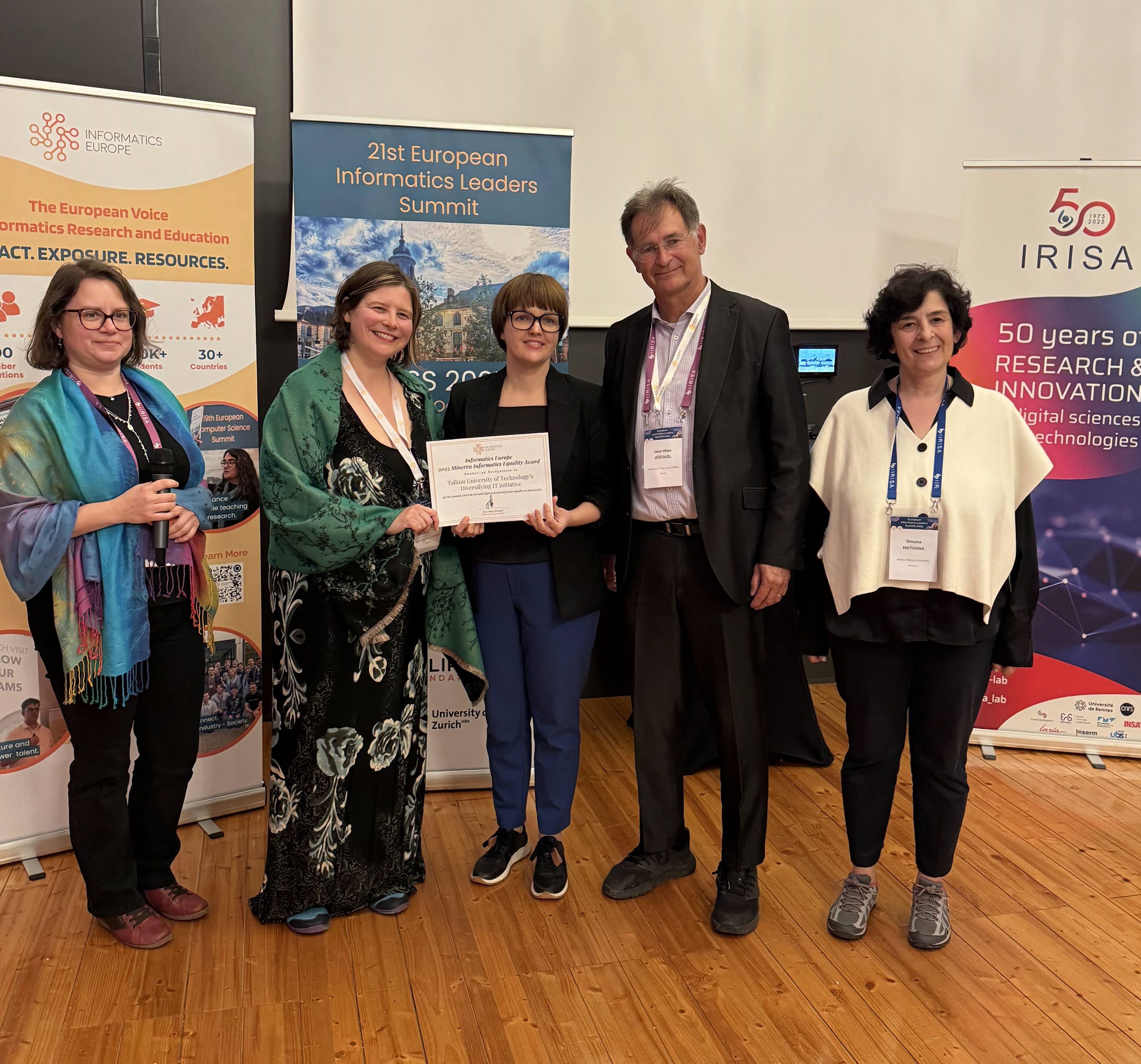 TalTechi IT mitmekesistamise programmi esindajad võtavad vastu Informatics Europe auhinda 21. Euroopa Informaatika Liidrite Tippkohtumisel. Pildil on viis inimest, kes hoiavad käes aukirja Informatics Europe ja IRISA logodega stendide ees.