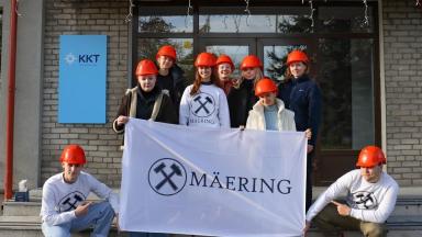a group of young people in orange helmets holdig up a sign