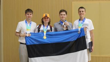 four young men with medals holding Estonian flag
