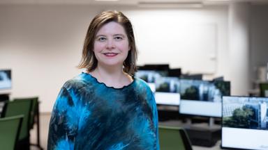 Birgy Lorenz seisab IT-Kolledži arvutiklassis, taustal roheliste toolidega töökohad ja arvutiekraanid.