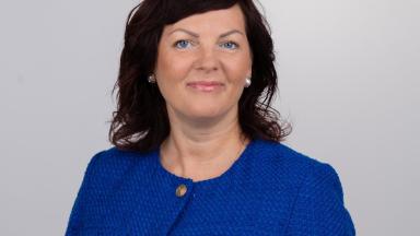 Naine sinises jakis, tumepruunide juuste ja pärlkõrvarõngastega, professionaalne portreefoto.