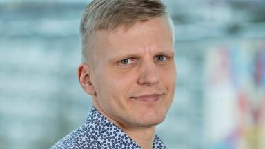 Tarvo Treier, TalTechi teadur, sinise mustrilise särgi ja heledahallikas soenguga, poolpöördes portreefoto hägusa taustaga.