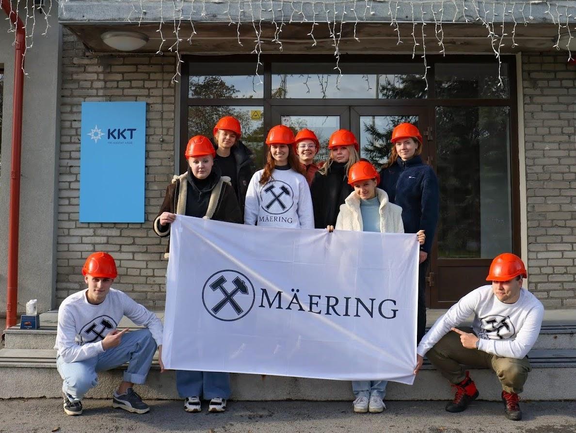 a group of young people in orange helmets holdig up a sign