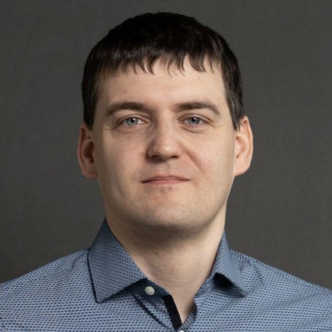 Portreefoto mehest, kes vaatab otse kaamerasse. Tal on lühikesed tumedad juuksed ja seljas sinakas mustriline nööpidega särk. Taust on neutraalne ja ühtlane, sobides ametlikuks profiilipildiks.